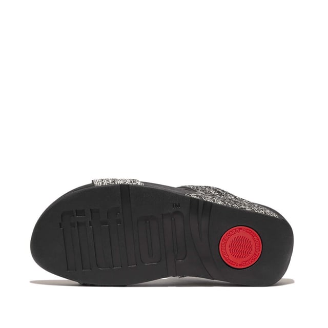 Women's Fit Flop Lulu Shimmerweave Sliders in Black De Lulu slippers van FitFlop zijn klassiekers. Blijvend populair, ze zijn zacht gevoerd en kunnen omhoog of omlaag gekleed worden. Ze staan op FitFlop's legendarische super dempende Microwobbleboard™ tussenzool. Dit seizoen uitgevoerd in een glinsterende structuurstof met een chique 'tweedy' uitstraling. Afgerand met metallic parelmoeren biezen van imitatieleer voor extra glans. Subtiel glinsterende sandalen die je overal bij kunt dragen en prachtig zijn van dag tot nacht.