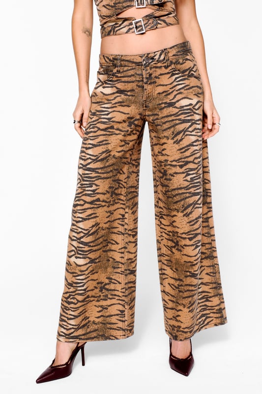 Bold tiger print denim jeans for a fierce look
        Straight leg cut for a classic silhouette
        High-waisted design for a flattering fit
        Wide leg openings for a trendy, relaxed style
        Versatile design suitable for day-to-night wear
    
    Make a statement with these eye-catching tiger print straight leg jeans from NastyGal. The bold pattern adds a touch of wild glamour to your wardrobe, perfect for those who dare to stand out. The straight leg cut offers a timeless silhouette that flatters various body types, while the high-waisted design accentuates your curves. For a night out on the town, pair these jeans with a sleek black bodysuit and strappy heels to let the print take centre stage. Add a leather jacket for an edgy touch, or dress them down with a simple white tee and trainers for a more casual look. These versatile jeans are ideal for transitioning from day to night, making them a must-have addition to your going-out wardrobe. Whether you're hitting the club or meeting friends for drinks, these NastyGal jeans will ensure you're turning heads for all the right reasons.