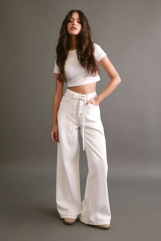Wide leg silhouette for a relaxed, on-trend look
        High-rise waist with belt loops for a flattering fit
        Removable fabric belt for versatile styling options
        Classic five-pocket design for practicality
        Ankle-grazing length perfect for showcasing footwear
    
    Make a bold statement with these eye-catching wide leg jeans from NastyGal. The relaxed silhouette offers both comfort and style, whilst the high-rise waist cinches you in at your smallest point. The removable fabric belt allows for customisable styling - wear it looped through for a defined waist or remove it for a more laid-back vibe. These versatile trousers transition effortlessly from day to night. For a casual daytime look, pair with a cropped tank top and trainers. When the sun sets, swap your flats for chunky platform boots and add a biker jacket for an edgy evening ensemble. Perfect for family gatherings, brunch dates, or casual Fridays at the office, these jeans will quickly become your go-to for effortless style.
