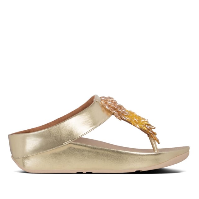 Doe de Rumba...met deze glinsterende, sierlijke teenslippers. Het slanke bovenwerk is bezaaid met een glanzende zwierige franje van veelkleurige 'kristallen' kralen (helder gekleurd en metallic). Op FitFlop's legendarische Microwobbleboard™ tussenzolen voor onovertroffen comfort en demping, de hele dag door. Trek ze aan en ga op zoek naar een feestje! Hier in zacht metallic kunstleer.
