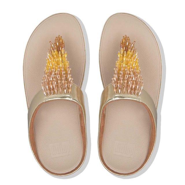 Doe de Rumba...met deze glinsterende, sierlijke teenslippers. Het slanke bovenwerk is bezaaid met een glanzende zwierige franje van veelkleurige 'kristallen' kralen (helder gekleurd en metallic). Op FitFlop's legendarische Microwobbleboard™ tussenzolen voor onovertroffen comfort en demping, de hele dag door. Trek ze aan en ga op zoek naar een feestje! Hier in zacht metallic kunstleer.