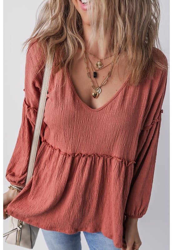 Blusa de color sólido en rojo mineral  
Tejido texturizado para mayor profundidad  
Detalle de volantes en los bordes  
Escote en V para un aspecto elegante  
Mangas abullonadas para una silueta dramática  
Diseño versátil y atemporal  
Material: 85% Poliéster 10% Algodón 5% Elastano