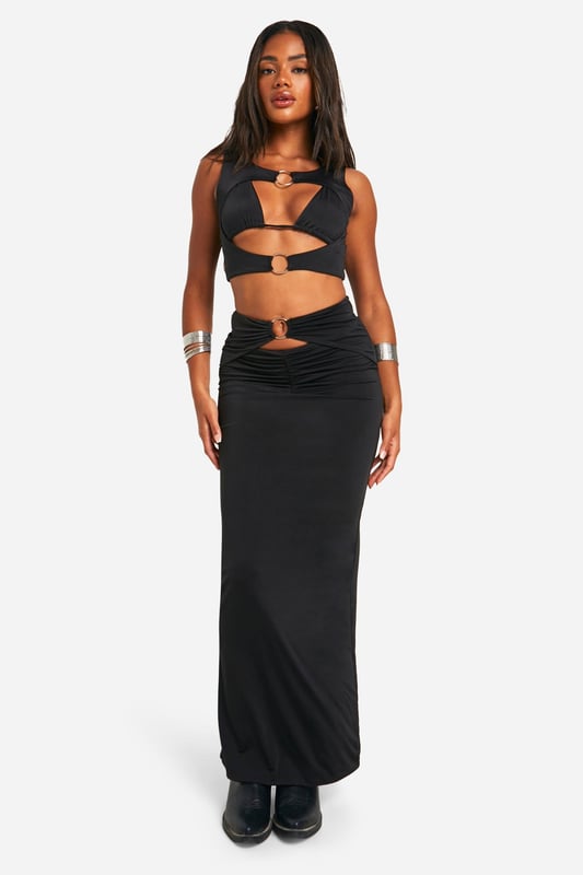 Daring cut-out design with O-ring details
        Floor-sweeping maxi length for dramatic flair
        Figure-hugging silhouette accentuates curves
        Ruched detailing at the waist for added texture
        Versatile piece suitable for various evening events
    
    Make a bold statement at your next festival or night out with this eye-catching cut-out maxiskirt. The daring design features strategically placed O-ring details that add an edgy touch to your ensemble. The figure-hugging silhouette and floor-sweeping length create a striking look that's sure to turn heads. Style it with a cropped top and chunky boots for a festival-ready outfit, or pair it with strappy heels and statement jewellery for a night on the town. The ruched detailing at the waist adds texture and interest, while also flattering your figure. This versatile piece can be dressed up or down, making it a must-have addition to your wardrobe for various evening occasions. Whether you're dancing the night away or enjoying drinks with friends, this maxiskirt will help you project confidence and style.