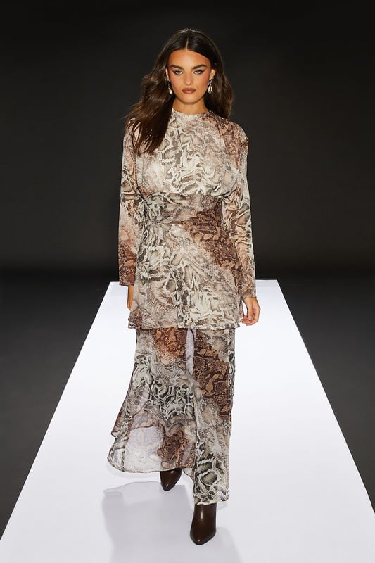 Chiffon fabric for a lightweight, flowing silhouette
        Pleated bodice adds texture and visual interest
        Sheer skirt creates an alluring, layered effect
        Maxi length for a dramatic, sweeping look
        Snake print pattern for a bold, edgy aesthetic
    
    Make a statement in this striking maxi dress from RUNWAY 1.8.1.8. The pleated bodice adds a touch of sophistication, while the sheer skirt creates an enchanting, layered effect that's perfect for daytime events. Style this versatile piece with ankle boots and a leather jacket for an edgy lunch date look, or pair it with flat sandals and oversized sunglasses for a chic garden party ensemble. The round neckline and long sleeves offer a modest touch, balancing the allure of the sheer skirt. This dress is ideal for those confident women who want to project a feminine yet daring style at casual gatherings or family events. The snake print pattern adds a bold twist to your wardrobe, ensuring you'll stand out in any crowd.