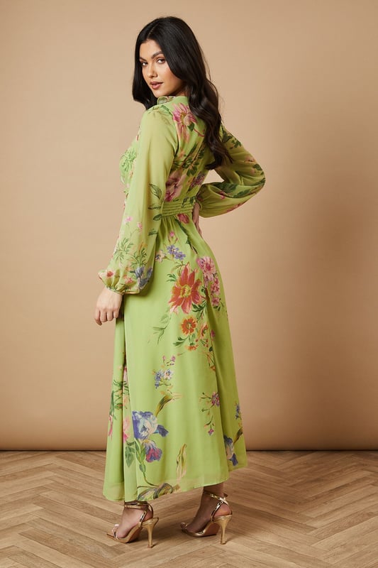 Enchanting floral print midi dress
        Flattering V-neckline with ruffle detail
        Long sleeves with elegant cuffs
        Cinched waist with matching fabric belt
        Stylish cut-out detail at the back
    
    Embrace the essence of feminine charm with this captivating printed midi dress from Oasis. The flowing chiffon fabric creates a graceful silhouette, while the vibrant floral pattern adds a touch of whimsy to your ensemble. Perfect for daytime events, this versatile piece can be styled for various casual occasions. Pair it with strappy sandals and a woven bag for a relaxed garden party look, or dress it down with white trainers and a denim jacket for a leisurely weekend brunch. The cut-out detail at the back adds a subtle hint of allure, making this dress a standout choice for family gatherings or afternoon tea with friends. Accessorise with delicate gold jewellery to complement the dress's romantic appeal and create a look that's both effortless and sophisticated.