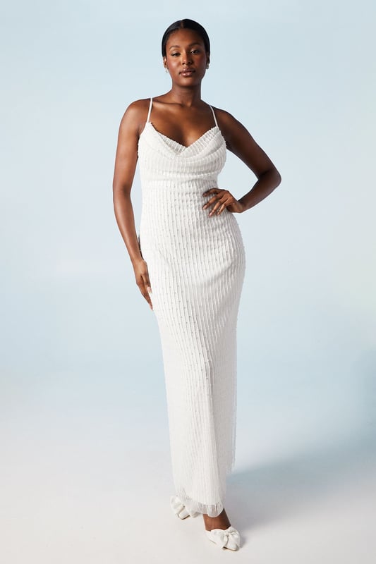 Elegant cowl neck design with intricate beading and pearl embellishments
        Figure-flattering column silhouette for a sleek and sophisticated look
        Delicate spaghetti straps offer a graceful and feminine touch
        Hand-stitched detailing showcases exquisite craftsmanship
        Midi length with a subtle back slit for ease of movement
    
    Make a stunning entrance on your special day with this captivating bridal midi dress from Coast. The cowl neck drapes beautifully, creating an alluring neckline that draws the eye. The column silhouette elongates your figure, whilst the beading and pearl embellishments add a touch of glamour and sparkle. Perfect for the modern bride who desires a blend of classic elegance and contemporary style. Pair with strappy heels and delicate drop earrings to complete your bridal ensemble. This versatile piece can also be styled for other formal occasions, such as engagement parties or sophisticated evening events, by adding a tailored blazer and statement clutch. The hand-stitched detailing ensures this dress is a true work of art, worthy of your most cherished moments.