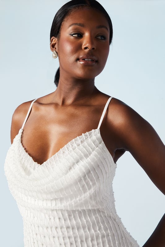 Elegant cowl neck design with intricate beading and pearl embellishments
        Figure-flattering column silhouette for a sleek and sophisticated look
        Delicate spaghetti straps offer a graceful and feminine touch
        Hand-stitched detailing showcases exquisite craftsmanship
        Midi length with a subtle back slit for ease of movement
    
    Make a stunning entrance on your special day with this captivating bridal midi dress from Coast. The cowl neck drapes beautifully, creating an alluring neckline that draws the eye. The column silhouette elongates your figure, whilst the beading and pearl embellishments add a touch of glamour and sparkle. Perfect for the modern bride who desires a blend of classic elegance and contemporary style. Pair with strappy heels and delicate drop earrings to complete your bridal ensemble. This versatile piece can also be styled for other formal occasions, such as engagement parties or sophisticated evening events, by adding a tailored blazer and statement clutch. The hand-stitched detailing ensures this dress is a true work of art, worthy of your most cherished moments.