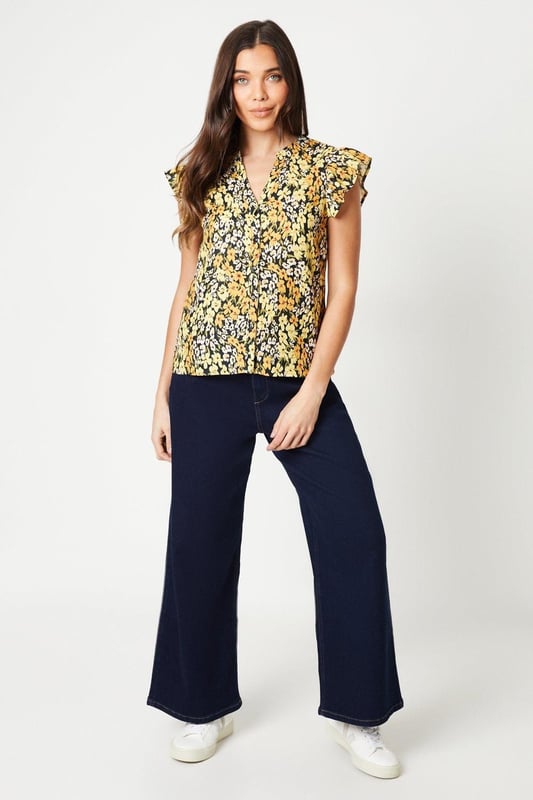 Floral printed woven top with a button-front design
Flattering ruffle trim along the neckline and cap sleeves
Relaxed fit through the body for effortless styling
Lightweight and breathable fabric for warm weather wear
Versatile length that can be tucked or left untucked

This petite floral top from Dorothy Perkins exudes a charming, feminine aesthetic that's perfect for smart casual occasions. The vibrant print and ruffle detailing add a touch of playfulness, while the button-front design lends a polished look. Pair it with tailored trousers or a pencil skirt for a sophisticated brunch ensemble, or dress it down with denim for a more relaxed vibe. Its versatility makes it an ideal choice for baby showers, afternoon teas, or any event where you want to look stylish yet comfortable.