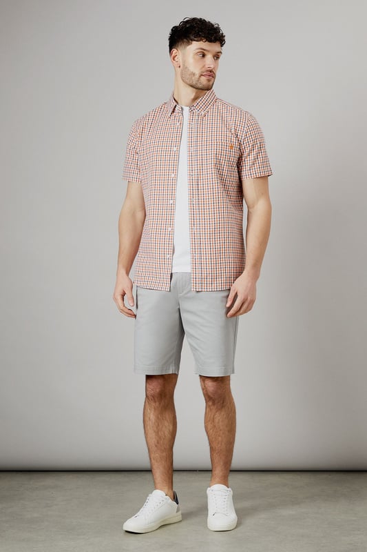 Vibrant check pattern for a stylish summer look
        Short sleeves for optimal comfort in warm weather
        Button-down collar for a smart-casual appearance
        Chest pocket adds a functional touch
        Versatile woven fabric suitable for various occasions
    
    Embrace the essence of laid-back sophistication with this eye-catching Helios check shirt from Maine. The striking pattern adds a dash of personality to your wardrobe, making it an ideal choice for casual outings and relaxed social gatherings. Style it effortlessly with light-coloured chino shorts and white trainers for a fresh summer ensemble. For a more polished look, pair it with tailored trousers and loafers. The short sleeves and breathable cotton fabric ensure you stay cool and comfortable, whether you're enjoying a family barbecue or meeting friends for a leisurely brunch. This versatile shirt transitions seamlessly from day to night, making it a must-have addition to your casual wardrobe. Layer it over a plain white t-shirt for added dimension, or wear it unbuttoned over a vest for a relaxed beach-ready look.