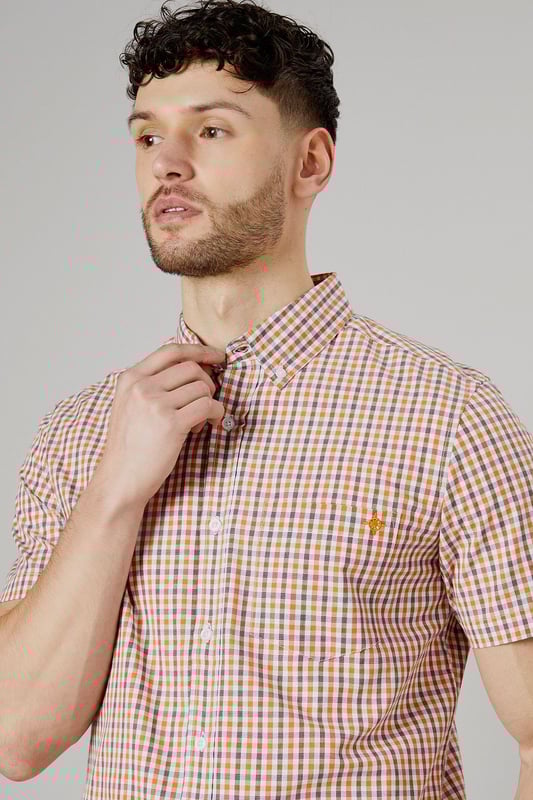 Vibrant check pattern for a stylish summer look
        Short sleeves for optimal comfort in warm weather
        Button-down collar for a smart-casual appearance
        Chest pocket adds a functional touch
        Versatile woven fabric suitable for various occasions
    
    Embrace the essence of laid-back sophistication with this eye-catching Helios check shirt from Maine. The striking pattern adds a dash of personality to your wardrobe, making it an ideal choice for casual outings and relaxed social gatherings. Style it effortlessly with light-coloured chino shorts and white trainers for a fresh summer ensemble. For a more polished look, pair it with tailored trousers and loafers. The short sleeves and breathable cotton fabric ensure you stay cool and comfortable, whether you're enjoying a family barbecue or meeting friends for a leisurely brunch. This versatile shirt transitions seamlessly from day to night, making it a must-have addition to your casual wardrobe. Layer it over a plain white t-shirt for added dimension, or wear it unbuttoned over a vest for a relaxed beach-ready look.