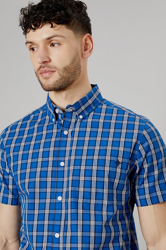 Vibrant check pattern for a bold, eye-catching look
        Short sleeves perfect for warmer weather
        Button-down collar for a smart-casual appearance
        Chest pocket adds a functional touch
        Regular fit allows for comfortable movement
    
    This Maine short sleeve shirt radiates casual charm with its striking check pattern. The bright blue hues create a lively aesthetic that's sure to turn heads. Crafted from pure cotton, it offers breathability and comfort ideal for summer days. Style it with light-coloured chinos and white trainers for a fresh daytime look perfect for weekend brunches or casual gatherings. For a more relaxed vibe, pair it with your favourite denim shorts and sandals for a seaside stroll. The versatile design allows for easy transition from day to night - simply swap your trainers for loafers and you're ready for an evening at the local pub. This shirt is a wardrobe essential that combines style and practicality, making it a go-to choice for various casual occasions throughout the warmer months.