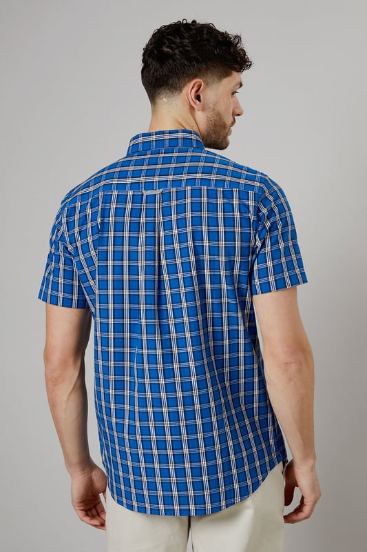 Vibrant check pattern for a bold, eye-catching look
        Short sleeves perfect for warmer weather
        Button-down collar for a smart-casual appearance
        Chest pocket adds a functional touch
        Regular fit allows for comfortable movement
    
    This Maine short sleeve shirt radiates casual charm with its striking check pattern. The bright blue hues create a lively aesthetic that's sure to turn heads. Crafted from pure cotton, it offers breathability and comfort ideal for summer days. Style it with light-coloured chinos and white trainers for a fresh daytime look perfect for weekend brunches or casual gatherings. For a more relaxed vibe, pair it with your favourite denim shorts and sandals for a seaside stroll. The versatile design allows for easy transition from day to night - simply swap your trainers for loafers and you're ready for an evening at the local pub. This shirt is a wardrobe essential that combines style and practicality, making it a go-to choice for various casual occasions throughout the warmer months.