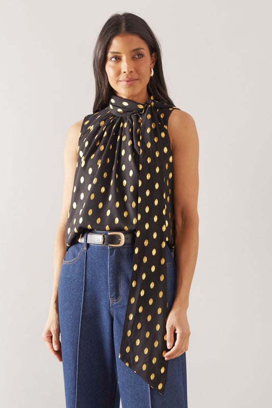 Sleeveless design for effortless warm-weather style
        High neck with elegant gathered detail
        Striking polka dot pattern throughout
        Flowing fabric for a graceful silhouette
        Versatile length suitable for various styling options
    
    This Wallis broderie collarless shirt radiates sophistication with its eye-catching polka dot pattern and refined high neck design. The gathered detail at the neckline adds a touch of elegance, while the sleeveless cut ensures comfort during warmer days. Perfect for daytime events, this versatile piece can be styled effortlessly for various casual occasions. Pair it with wide-leg trousers and a statement belt for a chic family gathering look, or team it with your favourite denim for a stylish brunch ensemble. The flowing fabric drapes beautifully, creating a flattering silhouette that's both comfortable and fashionable. Whether you're heading to a casual meetup with friends or a relaxed day out shopping, this shirt offers the perfect blend of comfort and style. Accessorise with delicate earrings and comfortable flats to complete your polished yet laid-back look.