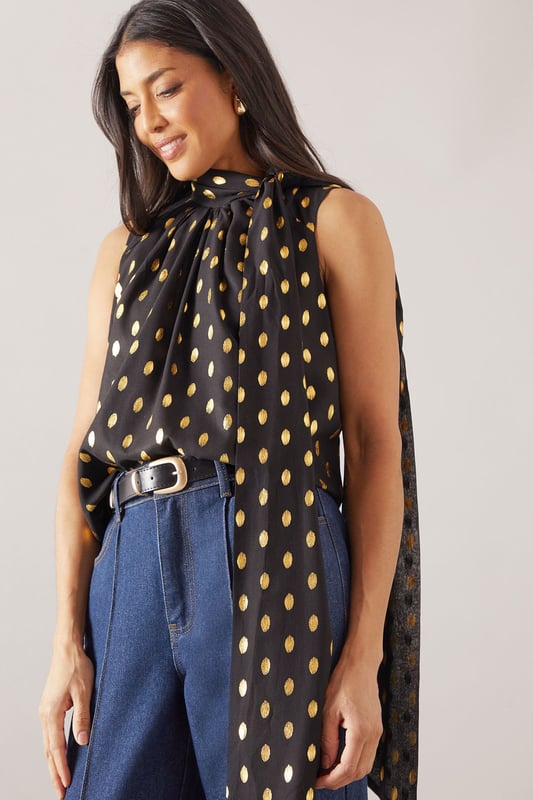 Sleeveless design for effortless warm-weather style
        High neck with elegant gathered detail
        Striking polka dot pattern throughout
        Flowing fabric for a graceful silhouette
        Versatile length suitable for various styling options
    
    This Wallis broderie collarless shirt radiates sophistication with its eye-catching polka dot pattern and refined high neck design. The gathered detail at the neckline adds a touch of elegance, while the sleeveless cut ensures comfort during warmer days. Perfect for daytime events, this versatile piece can be styled effortlessly for various casual occasions. Pair it with wide-leg trousers and a statement belt for a chic family gathering look, or team it with your favourite denim for a stylish brunch ensemble. The flowing fabric drapes beautifully, creating a flattering silhouette that's both comfortable and fashionable. Whether you're heading to a casual meetup with friends or a relaxed day out shopping, this shirt offers the perfect blend of comfort and style. Accessorise with delicate earrings and comfortable flats to complete your polished yet laid-back look.