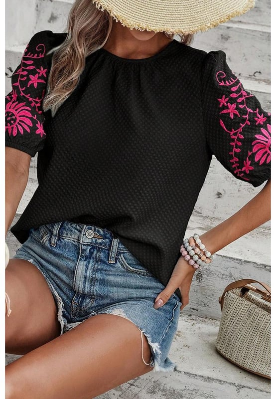 Camiseta de manga abullonada texturizada con bordado floral en negro  
Presenta un intrincado bordado floral en las mangas  
Adorables mangas abullonadas  
El tejido texturizado añade un toque de sofisticación  
Combínala con diversas prendas inferiores para looks versátiles  
Disponible en tallas unisex  
Material: 95% Poliéster 5% Elastano