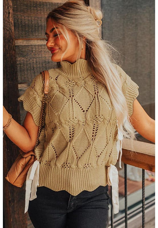 Color beige francés claro  
Diseño de punto ahuecado  
Terminación con volantes en el escote, mangas y dobladillo  
Escote alto  
Mangas cortas con volantes  
Laterales con detalles en volantes y acentos de lazo  
Silhouette relajada pero favorecedora  
Combina bien con pantalones, faldas y jeans  
Alta calidad y estilo chic  
Disponible en múltiples tamaños  
Material: 60% algodón, 40% acrílico