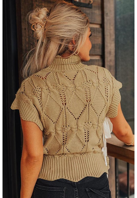 Color beige francés claro  
Diseño de punto ahuecado  
Terminación con volantes en el escote, mangas y dobladillo  
Escote alto  
Mangas cortas con volantes  
Laterales con detalles en volantes y acentos de lazo  
Silhouette relajada pero favorecedora  
Combina bien con pantalones, faldas y jeans  
Alta calidad y estilo chic  
Disponible en múltiples tamaños  
Material: 60% algodón, 40% acrílico