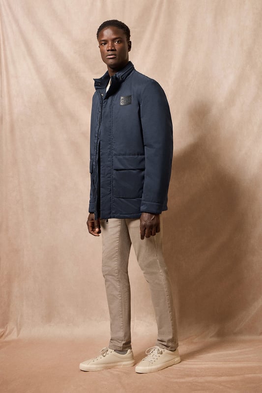 Der leichte Herrenparka Chelsea ist auf Funktionalität und Stil ausgelegt und kombiniert modernes Design mit klassischen Details. Die verdeckte Kapuze am Kragen sorgt für Vielseitigkeit und bietet bei Bedarf Schutz. Er verfügt über zwei aufgesetzte Taschen und eine verdeckte Brusttasche mit Reißverschluss. Der Hauptreißverschluss wird von einer Knopfleiste aus dem Hauptgewebe abgedeckt, die mit Druckknöpfen geschlossen wird und zusätzlichen Schutz vor Wind bietet. An der Innenseite befinden sich zwei Stopper an der Taille, mit denen Sie das Kleidungsstück nach Ihren Wünschen anpassen können. Details wie Zipper, Gummizüge und Stopper mit Logo sowie ein gummierter Aufnäher aus Twill mit dem Polo Club Logo auf der Brust verleihen dem Kleidungsstück eine exklusive und persönliche Note. Ideal für den modernen Mann, der ein leichtes, funktionelles Kleidungsstück mit einem Hauch von Raffinesse sucht.