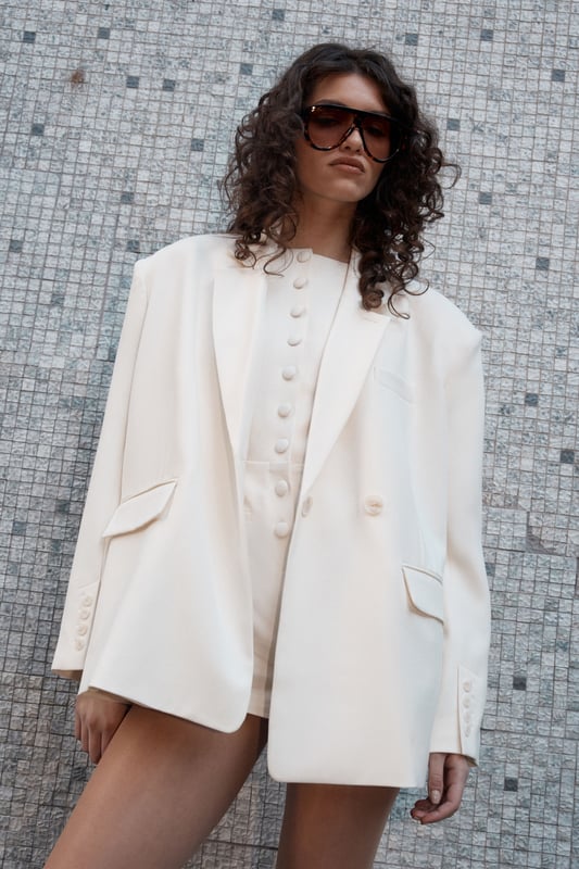 Tailored oversized fit for a contemporary silhouette
        Double-button front closure for versatile styling
        Notched lapels adding a classic touch
        Functional front pockets for practicality
        Long sleeves with button cuffs for a polished finish
    
    Make a bold statement in the office with this Essentials Tailored Oversized Double Button Blazer from NastyGal. This piece seamlessly blends professional polish with modern flair, perfect for the fashion-forward career woman. The oversized fit offers a contemporary twist on traditional tailoring, allowing for effortless layering over your favourite work attire. Style it with wide-leg trousers and a crisp white shirt for a chic, put-together look that commands attention in the boardroom. For a more relaxed approach, throw it over a turtleneck and tailored trousers. The versatility of this blazer makes it an indispensable addition to your workwear wardrobe, easily transitioning from important client meetings to after-work drinks with colleagues. Its timeless design ensures it will remain a staple in your professional attire for seasons to come.
