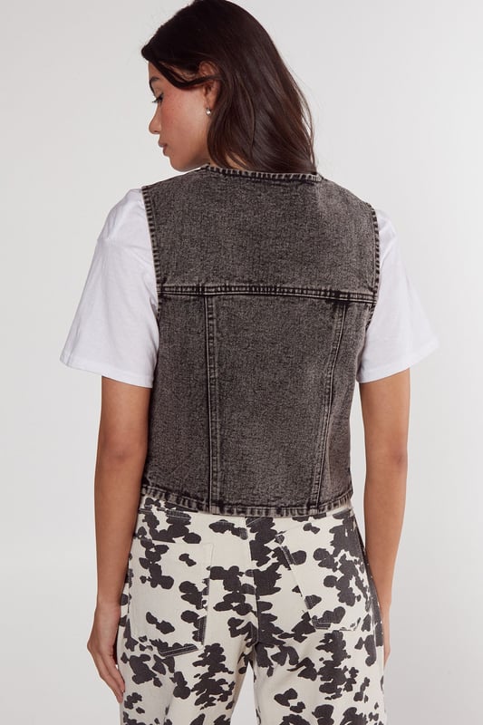 Sleeveless denim gilet with a trendy tie-front design
        Cropped length for a modern, fashion-forward silhouette
        Distinctive contrast stitching adds visual interest
        Two functional front patch pockets for practicality
        Versatile layering piece suitable for various casual looks
    
    This NastyGal tie front denim gilet is the perfect addition to your casual wardrobe, offering a blend of style and versatility. The cropped silhouette and tie-front detail create a flattering shape, while the denim fabric provides a classic, timeless appeal. Style it over a crisp white tee and pair with the trendy printed wide-leg trousers as shown for a chic daytime ensemble. For a more relaxed look, throw it over a floaty summer dress or team with high-waisted jeans and trainers. This gilet is ideal for family gatherings, weekend brunches, or casual outings with friends. Its adaptable nature allows for easy transition from day to night - simply swap your flats for ankle boots and add some statement jewellery for an effortless evening look. The denim gilet is a wardrobe staple that will see you through multiple seasons, making it a smart investment for the fashion-savvy shopper.