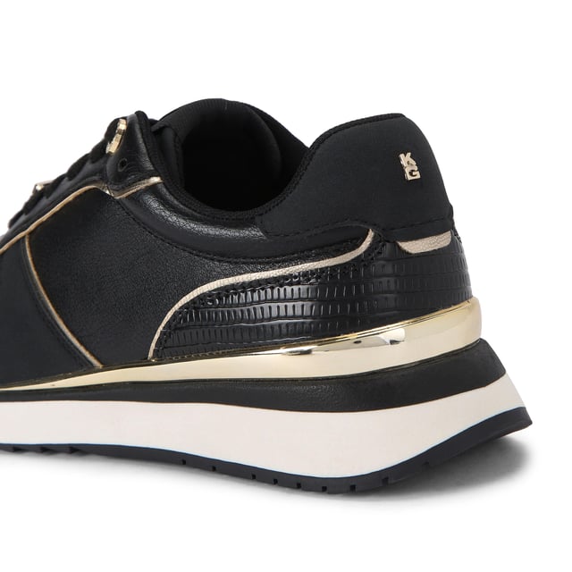 The List is a white sneaker with black and metallic gold panels across the upper. The front laces up with gold tone hardware details.