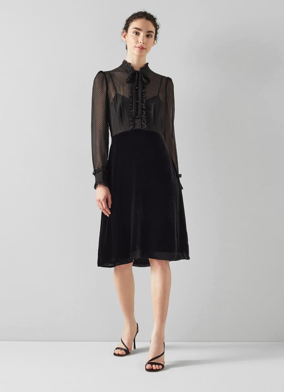 The little black dress is a party season favourite, and our Lucinda velvet dress is perfect for festive occasions. Crafted from soft black velvet, it has a sheer, spotty blouse top with a scallop edge collar, placket and cuffs, tie detail at the neckline and black buttons, and an A-line black velvet skirt. Wear it with strappy heels and a chic clutch.