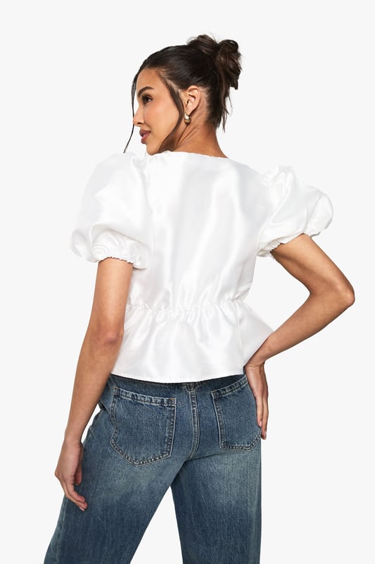Charming taffeta blouse with eye-catching lace-up detail
        Elegant puff sleeves for a romantic silhouette
        Ruffled front adds a touch of whimsy and femininity
        Peplum waist creates a flattering shape
        Versatile design suitable for both casual and dressy occasions
    
    This enchanting taffeta blouse is the perfect addition to your festive wardrobe. The lace-up detail at the neckline adds a playful touch, while the puff sleeves and ruffled front create a romantic, feminine silhouette. The peplum waist cinches in to flatter your figure, making it an ideal choice for Christmas parties or celebratory dinners. Style it with sleek black trousers and statement earrings for a chic evening look, or pair it with your favourite jeans and ankle boots for a more relaxed daytime ensemble. The versatility of this top allows you to dress it up or down, ensuring you'll shine at any holiday gathering. Whether you're sipping mulled wine at a festive market or dancing the night away at a Christmas bash, this blouse will keep you looking stylish and feeling confident throughout the season.