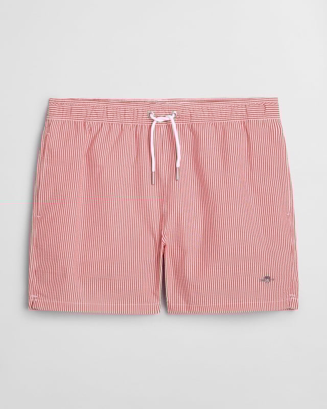  
 Crafted from 100% recycled polyester, these GANT swim shorts are essential for the summer season. Detailed with an all-over seersucker pattern and cut for a regular fit, they have a mid-thigh length and a regular waist. They feature an embroidered GANT shield on the left leg, side seam pockets, a single back pocket, and an elasticated drawstring waistband. This product is made with recycled polyester.

Regular fit
Mid-thigh length
Regular waist
GANT graphic embroidered on left leg

 85% Recycled Polyester, 15% Cotton 

922516001
 
