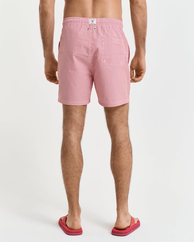  
 Crafted from 100% recycled polyester, these GANT swim shorts are essential for the summer season. Detailed with an all-over seersucker pattern and cut for a regular fit, they have a mid-thigh length and a regular waist. They feature an embroidered GANT shield on the left leg, side seam pockets, a single back pocket, and an elasticated drawstring waistband. This product is made with recycled polyester.

Regular fit
Mid-thigh length
Regular waist
GANT graphic embroidered on left leg

 85% Recycled Polyester, 15% Cotton 

922516001
 