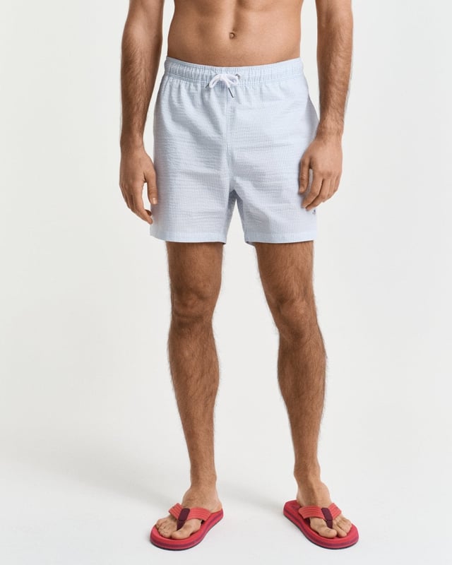  
 Crafted from 100% recycled polyester, these GANT swim shorts are essential for the summer season. Detailed with an all-over seersucker pattern and cut for a regular fit, they have a mid-thigh length and a regular waist. They feature an embroidered GANT shield on the left leg, side seam pockets, a single back pocket, and an elasticated drawstring waistband. This product is made with recycled polyester.

Regular fit
Mid-thigh length
Regular waist
GANT graphic embroidered on left leg

 85% Recycled Polyester, 15% Cotton 

922516001
 