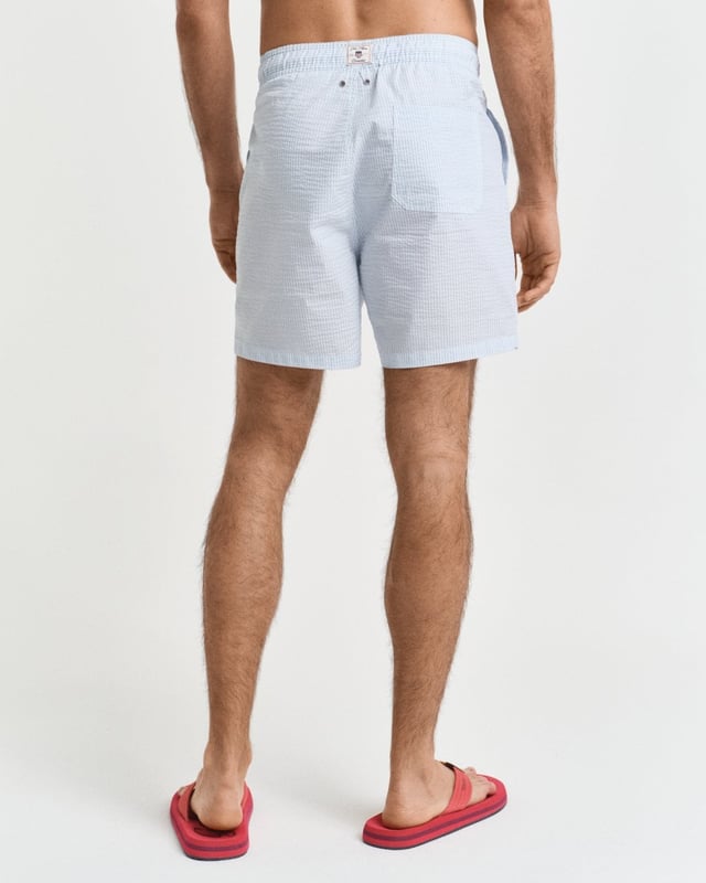  
 Crafted from 100% recycled polyester, these GANT swim shorts are essential for the summer season. Detailed with an all-over seersucker pattern and cut for a regular fit, they have a mid-thigh length and a regular waist. They feature an embroidered GANT shield on the left leg, side seam pockets, a single back pocket, and an elasticated drawstring waistband. This product is made with recycled polyester.

Regular fit
Mid-thigh length
Regular waist
GANT graphic embroidered on left leg

 85% Recycled Polyester, 15% Cotton 

922516001
 