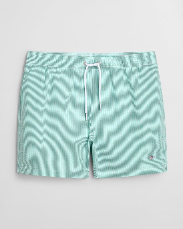  
 Crafted from 100% recycled polyester, these GANT swim shorts are essential for the summer season. Detailed with an all-over seersucker pattern and cut for a regular fit, they have a mid-thigh length and a regular waist. They feature an embroidered GANT shield on the left leg, side seam pockets, a single back pocket, and an elasticated drawstring waistband. This product is made with recycled polyester.

Regular fit
Mid-thigh length
Regular waist
GANT graphic embroidered on left leg

 85% Recycled Polyester, 15% Cotton 

922516001
 