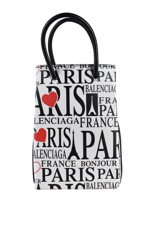 Bolso Balenciaga Shopping North South XS.Piel blanca.Estampados turísticos  Bonjour Paris  en rojo y negro.Dos asas negras.Logotipo en el interior.Cierre a presión plateado.Dimensiones: alto: 18 cm x ancho: 13 cm x fondo: 5 cm. Made in Italy.