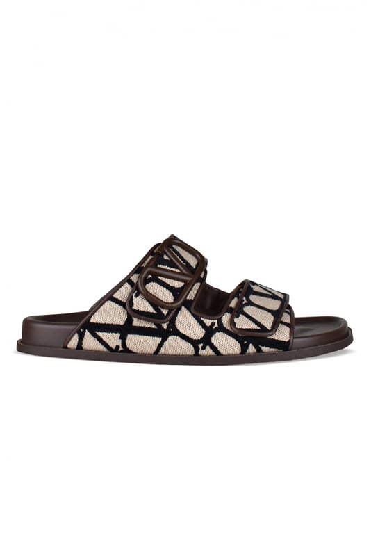 Sandalias Valentino de piel marrón.Lona iconográfica beige con logo monograma negro.Ribete marrón con logotipo V de la firma.Cierre de velcro delantero.Suela de goma.Made in Italy.