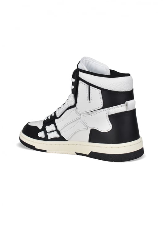 Sneakers altas Skel Top Amiri de piel negra y blanca.Inserciones de cuero blanco formando un esqueleto.Lengüeta de nailon blanco con logotipo.Placa metálica con el logotipo en la parte delantera.Suela fina de goma negra y blanca con logotipo.Cordones blancos.Puntera redonda.