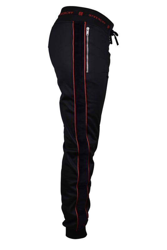 Un jogging de Givenchy.Franja lateral de terciopelo negro con línea roja. Cintura con cordón y puntera de cuero.Logotipo rojo de Givenchy en la cintura. Dos bolsillos con cremallera. Apriete en la parte inferior.Interior de vellón.100% polyester.Made in Italy.