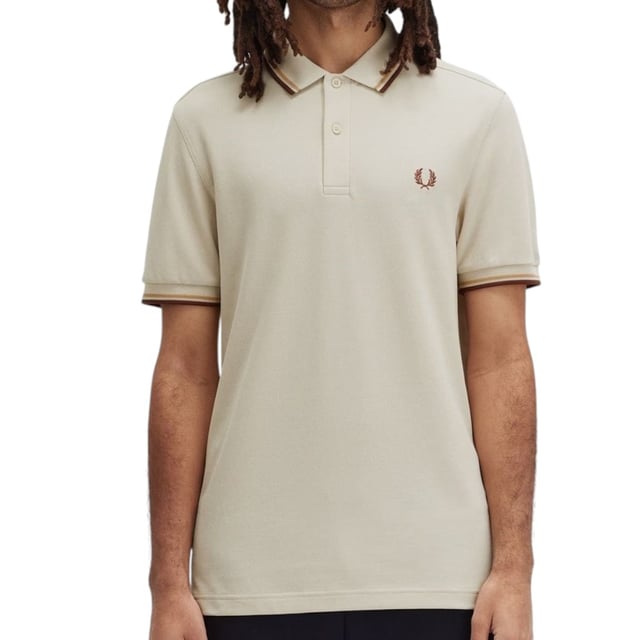 Das Twin Tipped Fred Perry Poloshirt von Fred Perry ist ein kurzärmeliges Poloshirt aus dem klassischen Baumwollpiqué von Fred Perry – in einer modernen Neuinterpretation von Freds berühmtem, schlankem Schnitt. Erhältlich in einer Vielzahl von Farbvarianten – jede mit ihrer eigenen Geschichte. Mit dem charakteristischen Fred Perry Lorbeerkranz-Logo auf der Brust und der typischen Twin Tipping-Verzierung an Kragen und Ärmelbündchen.