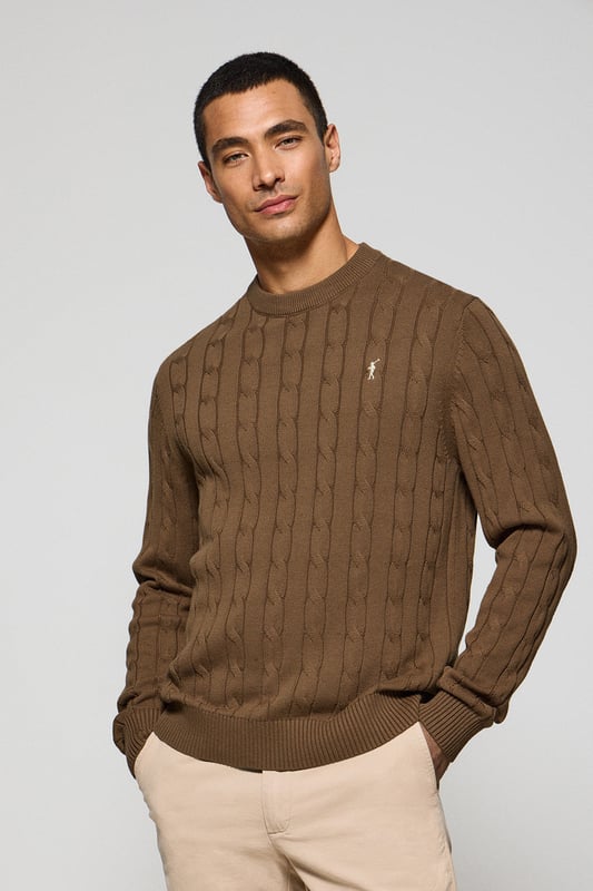 Unser Zopfstrickpullover für Herren ist ein Synonym für Eleganz und Komfort. Sein einzigartiges Flechtmuster verleiht ihm Struktur und Raffinesse, während gerippte Details an Kragen, Ärmeln und Saum für einen guten Sitz und ein raffiniertes Finish sorgen. Das dezente marineblaue Nahtband am Kragen mit Polo Club Logo unterstreicht die Eleganz dieses Modells. Die emblematische Rigby Go Stickerei in Kontrastfarbe auf der Brust unterstreicht seine einzigartige Optik. Ideal für einen eleganten und zeitlosen Look.