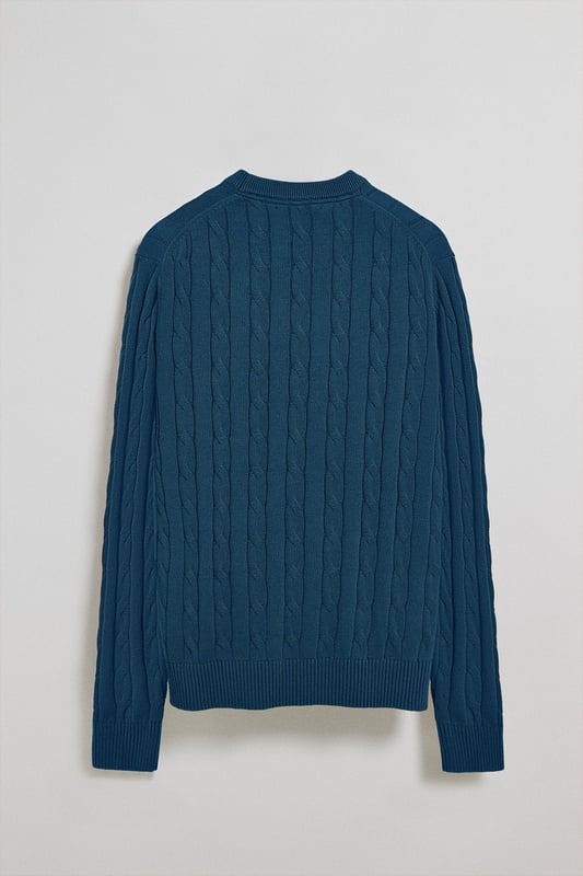 Unser Zopfstrickpullover für Herren ist ein Synonym für Eleganz und Komfort. Sein einzigartiges Flechtmuster verleiht ihm Struktur und Raffinesse, während gerippte Details an Kragen, Ärmeln und Saum für einen guten Sitz und ein raffiniertes Finish sorgen. Das dezente marineblaue Nahtband am Kragen mit Polo Club Logo unterstreicht die Eleganz dieses Modells. Die emblematische Rigby Go Stickerei in Kontrastfarbe auf der Brust unterstreicht seine einzigartige Optik. Ideal für einen eleganten und zeitlosen Look.