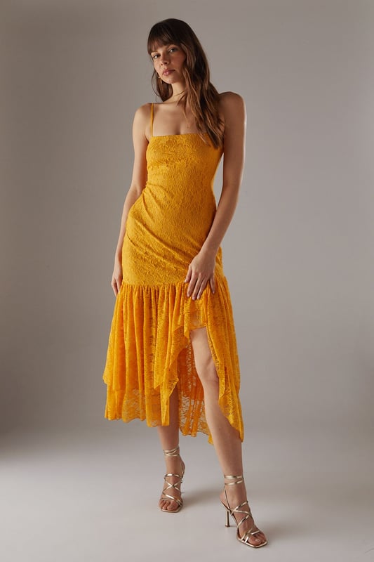 Delicate all-over lace fabric creates a romantic, feminine aesthetic
        Flattering drop waist silhouette with dramatic ruffle detail
        Elegant strappy neckline adds a contemporary touch
        Semi-sheer lace ruffle creates an asymmetric midi hemline
        Lined bodice ensures comfort and coverage where needed
    
    This striking Warehouse midi dress combines sophisticated design with bold femininity. The form-fitting bodice transitions into a playful drop waist ruffle, creating a silhouette that's both flattering and fashion-forward. The delicate lace fabric offers a beautiful textural contrast whilst the asymmetric hemline adds movement and drama. Style with strappy heels and a metallic clutch as shown for evening events, or dress down with leather mules and a tailored blazer for summer garden parties. Perfect for weddings, races or formal occasions where you want to make an impression, this versatile piece can be accessorised with statement jewellery for additional glamour or kept minimal to let the intricate lace detailing take centre stage. The strappy neckline frames the dcolletage beautifully, making this a confident choice for those special moments when you wish to command attention.