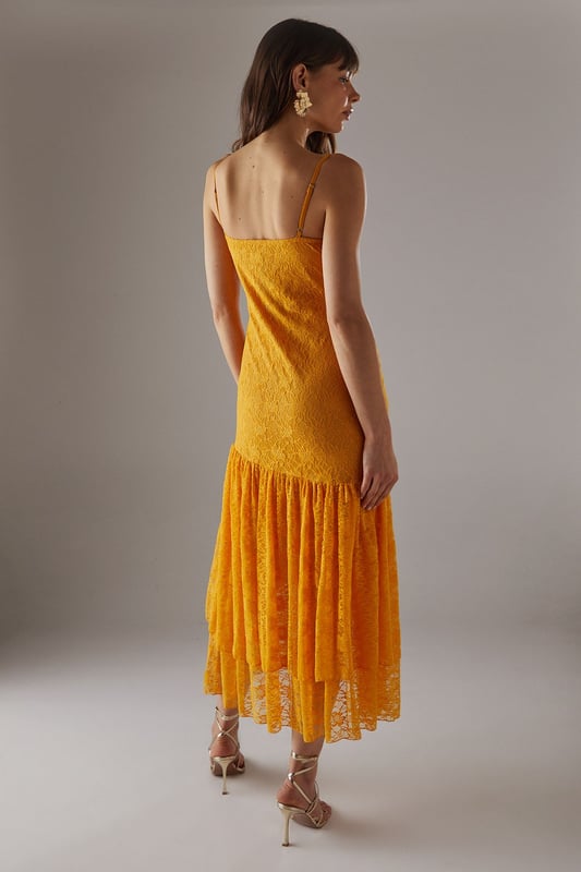Delicate all-over lace fabric creates a romantic, feminine aesthetic
        Flattering drop waist silhouette with dramatic ruffle detail
        Elegant strappy neckline adds a contemporary touch
        Semi-sheer lace ruffle creates an asymmetric midi hemline
        Lined bodice ensures comfort and coverage where needed
    
    This striking Warehouse midi dress combines sophisticated design with bold femininity. The form-fitting bodice transitions into a playful drop waist ruffle, creating a silhouette that's both flattering and fashion-forward. The delicate lace fabric offers a beautiful textural contrast whilst the asymmetric hemline adds movement and drama. Style with strappy heels and a metallic clutch as shown for evening events, or dress down with leather mules and a tailored blazer for summer garden parties. Perfect for weddings, races or formal occasions where you want to make an impression, this versatile piece can be accessorised with statement jewellery for additional glamour or kept minimal to let the intricate lace detailing take centre stage. The strappy neckline frames the dcolletage beautifully, making this a confident choice for those special moments when you wish to command attention.
