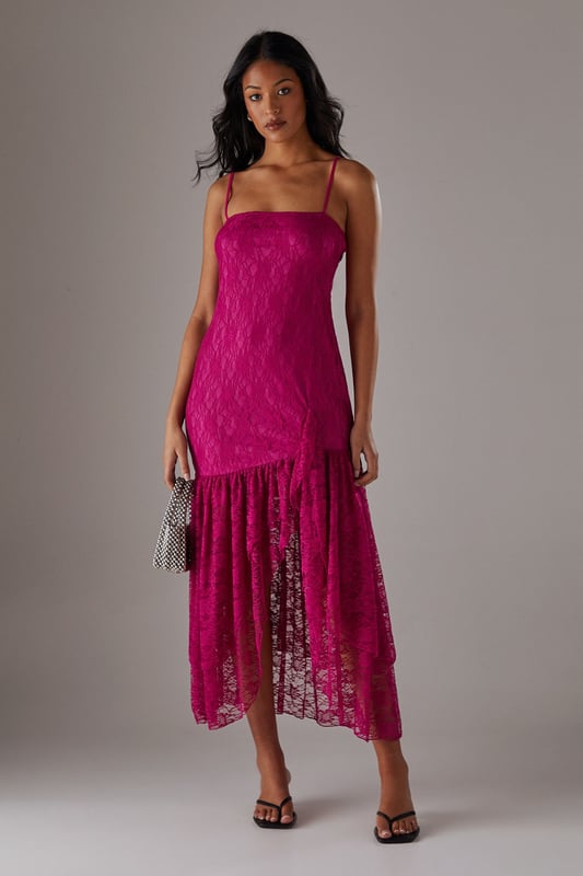 Delicate all-over lace fabric creates a romantic, feminine aesthetic
        Flattering drop waist silhouette with dramatic ruffle detail
        Elegant strappy neckline adds a contemporary touch
        Semi-sheer lace ruffle creates an asymmetric midi hemline
        Lined bodice ensures comfort and coverage where needed
    
    This striking Warehouse midi dress combines sophisticated design with bold femininity. The form-fitting bodice transitions into a playful drop waist ruffle, creating a silhouette that's both flattering and fashion-forward. The delicate lace fabric offers a beautiful textural contrast whilst the asymmetric hemline adds movement and drama. Style with strappy heels and a metallic clutch as shown for evening events, or dress down with leather mules and a tailored blazer for summer garden parties. Perfect for weddings, races or formal occasions where you want to make an impression, this versatile piece can be accessorised with statement jewellery for additional glamour or kept minimal to let the intricate lace detailing take centre stage. The strappy neckline frames the dcolletage beautifully, making this a confident choice for those special moments when you wish to command attention.