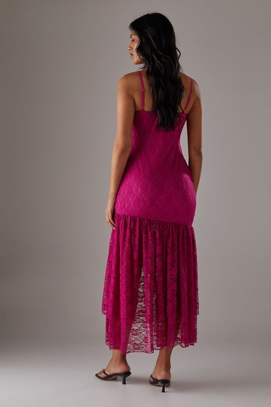 Delicate all-over lace fabric creates a romantic, feminine aesthetic
        Flattering drop waist silhouette with dramatic ruffle detail
        Elegant strappy neckline adds a contemporary touch
        Semi-sheer lace ruffle creates an asymmetric midi hemline
        Lined bodice ensures comfort and coverage where needed
    
    This striking Warehouse midi dress combines sophisticated design with bold femininity. The form-fitting bodice transitions into a playful drop waist ruffle, creating a silhouette that's both flattering and fashion-forward. The delicate lace fabric offers a beautiful textural contrast whilst the asymmetric hemline adds movement and drama. Style with strappy heels and a metallic clutch as shown for evening events, or dress down with leather mules and a tailored blazer for summer garden parties. Perfect for weddings, races or formal occasions where you want to make an impression, this versatile piece can be accessorised with statement jewellery for additional glamour or kept minimal to let the intricate lace detailing take centre stage. The strappy neckline frames the dcolletage beautifully, making this a confident choice for those special moments when you wish to command attention.