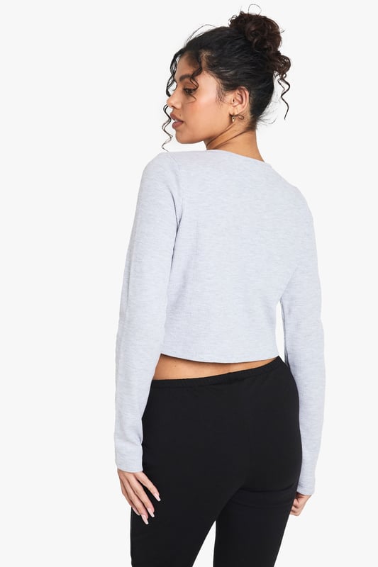 Textured waffle-knit fabric for added visual interest
        Cropped length perfect for high-waisted bottoms
        Scoop neckline for a flattering silhouette
        Button-front closure for adjustable styling
        Long sleeves ideal for layering or solo wear
    
    Embrace casual chic with this versatile waffle-knit top from Boohoo. The cropped silhouette and scoop neckline create a flattering frame, while the button-front detail adds a touch of intrigue. Perfect for those laid-back days, pair it with high-waisted jeans and trainers for a coffee run, or dress it up with a midi skirt and ankle boots for a family gathering. The textured fabric adds depth to your ensemble, making it an ideal choice for transitional weather. Layer it under a denim jacket for extra warmth, or wear it solo on warmer days. This top effortlessly bridges the gap between comfort and style, making it a must-have addition to your casual wardrobe. Whether you're running errands or meeting friends for a casual lunch, this top will keep you looking effortlessly put-together.