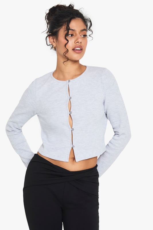 Textured waffle-knit fabric for added visual interest
        Cropped length perfect for high-waisted bottoms
        Scoop neckline for a flattering silhouette
        Button-front closure for adjustable styling
        Long sleeves ideal for layering or solo wear
    
    Embrace casual chic with this versatile waffle-knit top from Boohoo. The cropped silhouette and scoop neckline create a flattering frame, while the button-front detail adds a touch of intrigue. Perfect for those laid-back days, pair it with high-waisted jeans and trainers for a coffee run, or dress it up with a midi skirt and ankle boots for a family gathering. The textured fabric adds depth to your ensemble, making it an ideal choice for transitional weather. Layer it under a denim jacket for extra warmth, or wear it solo on warmer days. This top effortlessly bridges the gap between comfort and style, making it a must-have addition to your casual wardrobe. Whether you're running errands or meeting friends for a casual lunch, this top will keep you looking effortlessly put-together.
