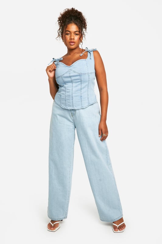 Corset-style denim top with structured panelling
        Sweetheart neckline for a feminine touch
        Adjustable bow-tie shoulder straps
        Exposed back zip for easy wear
        Versatile design suitable for various body types
    
    Embrace your curves with this chic plus-size denim corset top from Boohoo. The structured panelling creates a flattering silhouette, while the sweetheart neckline adds a touch of romance. The adjustable bow-tie straps allow for a customised fit and lend a playful element to the design. Perfect for casual outings, this top pairs brilliantly with wide-leg jeans for a coordinated denim look, or with a flowing skirt for a balanced ensemble. Layer it under a lightweight cardigan for cooler evenings or wear it solo to showcase its unique details. Ideal for family gatherings or brunches with friends, this versatile piece can be dressed up with statement earrings and wedges or kept casual with trainers and a denim jacket. The exposed back zip ensures easy dressing, making this corset top a practical yet stylish addition to your wardrobe.