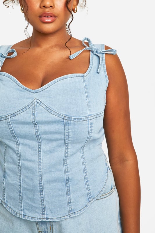 Corset-style denim top with structured panelling
        Sweetheart neckline for a feminine touch
        Adjustable bow-tie shoulder straps
        Exposed back zip for easy wear
        Versatile design suitable for various body types
    
    Embrace your curves with this chic plus-size denim corset top from Boohoo. The structured panelling creates a flattering silhouette, while the sweetheart neckline adds a touch of romance. The adjustable bow-tie straps allow for a customised fit and lend a playful element to the design. Perfect for casual outings, this top pairs brilliantly with wide-leg jeans for a coordinated denim look, or with a flowing skirt for a balanced ensemble. Layer it under a lightweight cardigan for cooler evenings or wear it solo to showcase its unique details. Ideal for family gatherings or brunches with friends, this versatile piece can be dressed up with statement earrings and wedges or kept casual with trainers and a denim jacket. The exposed back zip ensures easy dressing, making this corset top a practical yet stylish addition to your wardrobe.