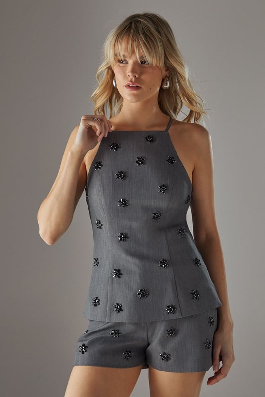 Elegant square neckline with thin straps for a feminine silhouette
        Delicate embellishment pattern scattered across the fabric for subtle sparkle
        Sleek, fitted design that contours to your shape
        Versatile woven fabric with slight stretch for comfort
        Coordinating shorts create a chic co-ord set perfect for evening occasions
    
    This embellished square neck top from Warehouse delivers confident sophistication with its contemporary design. The striking square neckline frames your dcolletage beautifully, while the scattered embellishments catch the light as you move, adding dimension to your evening look. Style with the matching shorts as shown for a coordinated ensemble that commands attention, or pair with tailored trousers and strappy heels for more formal gatherings. Add statement earrings and a clutch bag to complete your night-out ensemble. The sleek silhouette works wonderfully for drinks with friends, club nights, or sophisticated bar hopping - anywhere you want to showcase your fashion-forward sensibility while maintaining an effortlessly chic appearance. Machine washable for practicality without compromising on style.