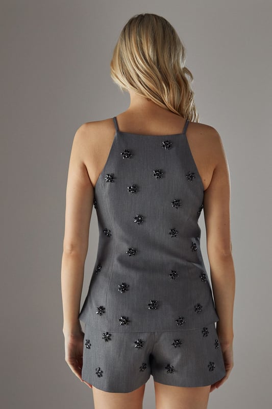 Elegant square neckline with thin straps for a feminine silhouette
        Delicate embellishment pattern scattered across the fabric for subtle sparkle
        Sleek, fitted design that contours to your shape
        Versatile woven fabric with slight stretch for comfort
        Coordinating shorts create a chic co-ord set perfect for evening occasions
    
    This embellished square neck top from Warehouse delivers confident sophistication with its contemporary design. The striking square neckline frames your dcolletage beautifully, while the scattered embellishments catch the light as you move, adding dimension to your evening look. Style with the matching shorts as shown for a coordinated ensemble that commands attention, or pair with tailored trousers and strappy heels for more formal gatherings. Add statement earrings and a clutch bag to complete your night-out ensemble. The sleek silhouette works wonderfully for drinks with friends, club nights, or sophisticated bar hopping - anywhere you want to showcase your fashion-forward sensibility while maintaining an effortlessly chic appearance. Machine washable for practicality without compromising on style.