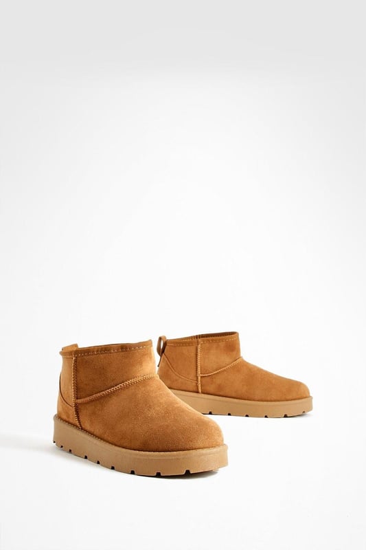 Ultra mini design for a trendy, compact silhouette
        Cosy synthetic suede upper for warmth and comfort
        Slip-on style for easy wear
        Durable synthetic outer sole for traction
        Versatile ankle height suitable for various outfits
    
    Step into comfort and style with these ultra mini cosy boots from Boohoo. Perfect for the fashion-forward woman who values both trend and practicality, these boots offer a snug fit that's ideal for chilly days. The ankle-height design makes them incredibly versatile, pairing effortlessly with everything from skinny jeans to midi skirts. For a laid-back look, team them with oversized knitwear and leggings, or dress them up with a flowy dress and tights for casual outings. These boots are a must-have for family gatherings, coffee dates, or weekend shopping trips. Their compact size makes them an excellent choice for travel, easily fitting into your luggage without sacrificing style. Embrace the cosy-chic trend and make these ultra mini boots your go-to footwear for comfortable, on-trend casual wear.